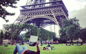 People relax on the grass near the Eiffel Tower