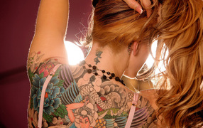 Рыжая девушка с татуировкой на спине