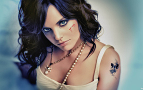 Шрам на щеке и татуировка на плече у девушки