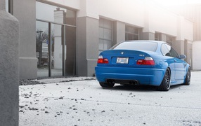 Голубой BMW на бетонной площадке у дома