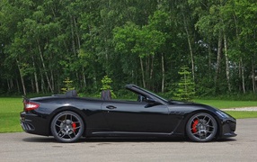 Black convertible Maserati in a forest