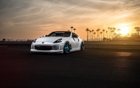 White Nissan 370Z on a background of palm trees and sunset