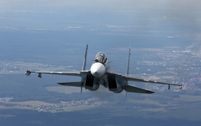 Самолет СУ-27 летит над городом