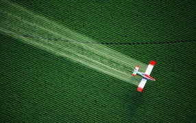 Самолет распыляет удобрения над полем