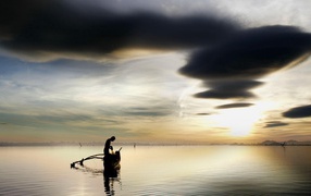 Рыбак достает улов из своей лодки