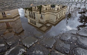 Отражение городского здания в луже