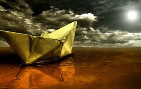 Корабль из бумаги на мокром песке