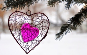 Украшение в виде сердца висит на ветке ели