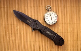 Часы и нож на бамбуковом коврике