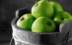 A bucket of wood with green apples