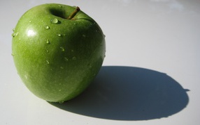 Зеленое яблоко на белой поверхности