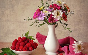 Saucer with raspberries and a bouquet of flowers