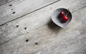 Two red cherries in a ceramic cup