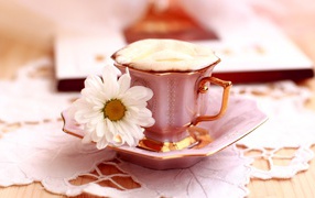 Кофе с пенкой и ромашка на блюдце