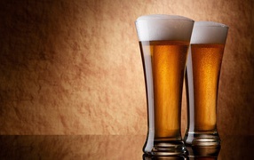 Два бокала пива, коричневый фон
