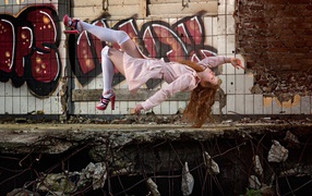 Девушка выполняет трюк на фоне граффити