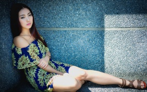 Девушка сидит в тени у гранитной стены