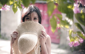 Азиатская девушка прикрыла лицо шляпой