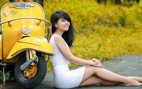 Азиатская девушка у желтого мотороллера