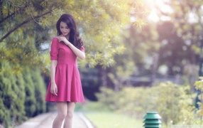 Азиатка в красном платье гуляет в саду