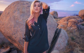 Блондинка стоит у большого валуна