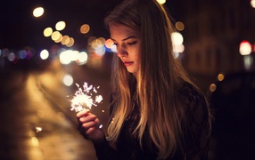 Девушка держит в руке бенгальский огонь