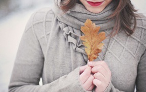 Девушка держит в руках желтый лист