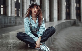 Девушка в берете сидит на краю дорожки