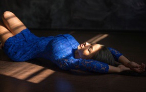 Девушка в голубом кружевном платье лежит на полу