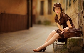 Девушка в коричневой одежде сидит у дороги