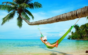 Девушка в зеленом гамаке под пальмой