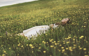 Девушка лежит в поле среди одуванчиков