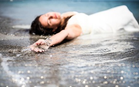 Девушка лежит в волне прибоя