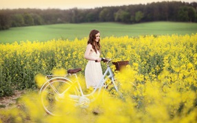 Девушка на велосипеде среди желтых цветов