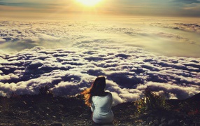 Девушка сидит и смотрит на облака