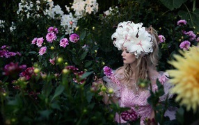 Девушка сидит в цветнике