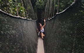 Girl sitting on a suspension bridge