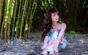 Девушка сидит на земле в бамбуковом лесу