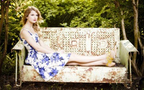 Девушка сидит на железной скамье в саду