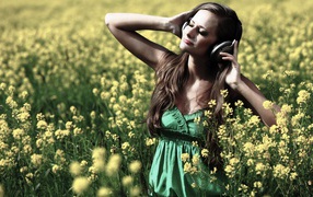 Девушка стоит среди цветов в наушниках