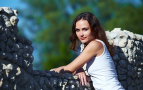 Девушка стоит у забора из камня