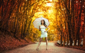 Девушка с белым зонтом стоит в осеннем парке
