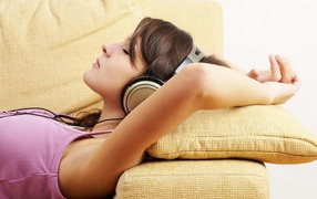 Девушка в наушниках лежит на подушках