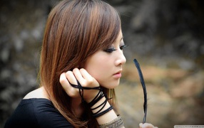 Японская девушка смотрит на черное перо