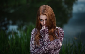 Рыжая девушка в свитере на фоне водоема