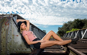 Блондинка в шляпе позирует на железной дороге