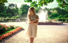 Блондинка в парке на фоне фонтана