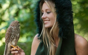 Девушка в меховой накидке держит на руке птицу