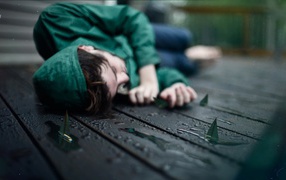 Девушка в зеленом лежит на мокрых досках