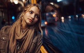 Девушка прислонилась к окну вечернего автобуса